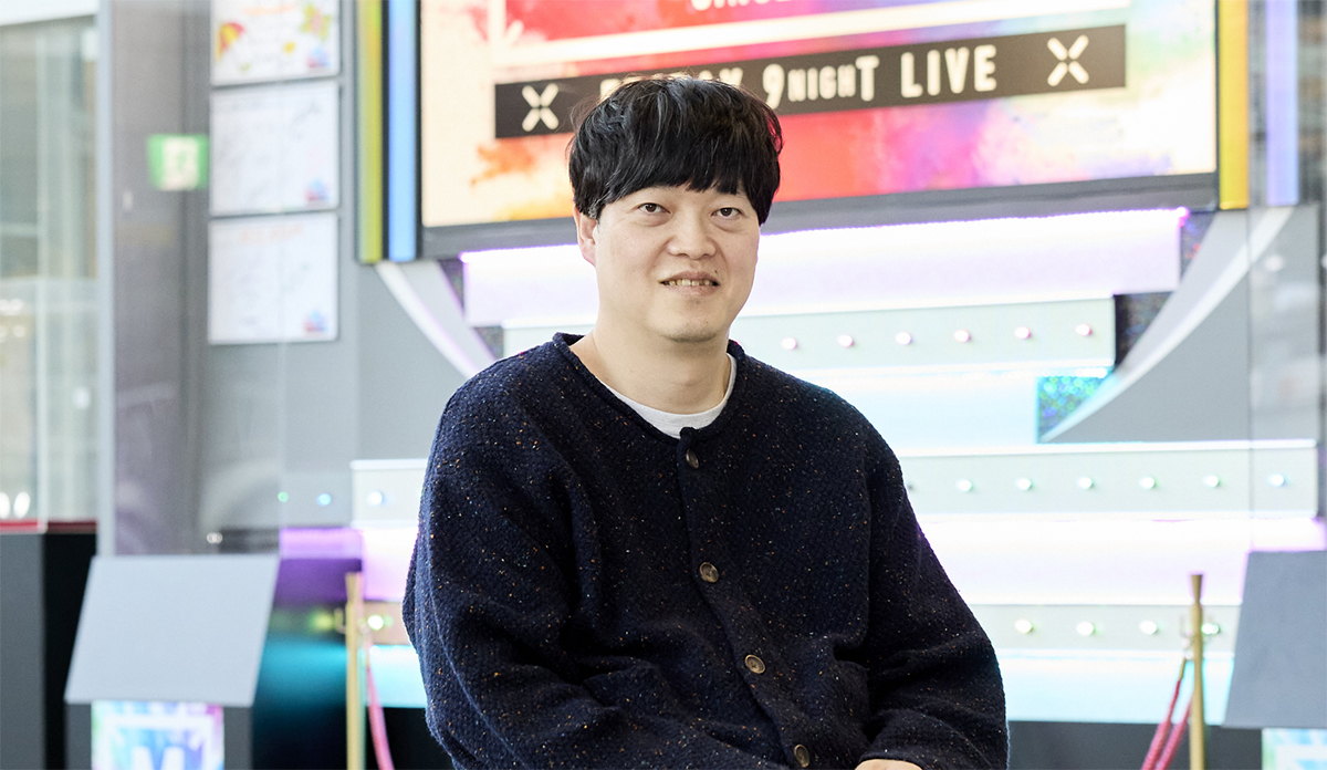 テレビ朝日本社内にある「ミュージックステーション」の展示を背景に、微笑む清野さんのポートレート写真。