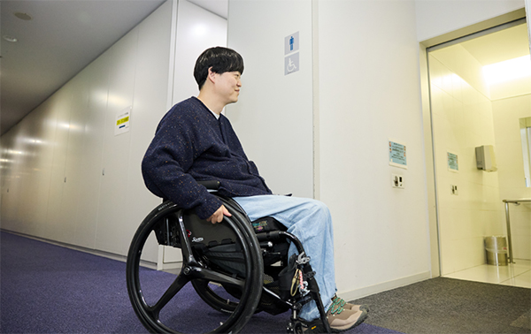 車椅子で多目的トイレに入っていく清野さんの様子。