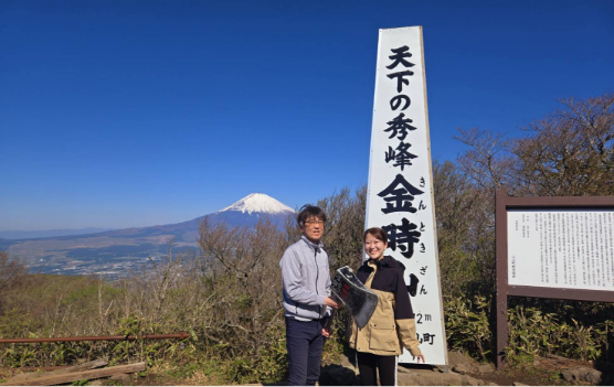 「天下の秀峰金時山」と書かれた石碑の前で、家族と並んで立つ髙島さん。背後には富士山が見える。